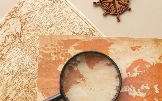 Antique maps, a magnifying glass and a carved wooden compass rose.