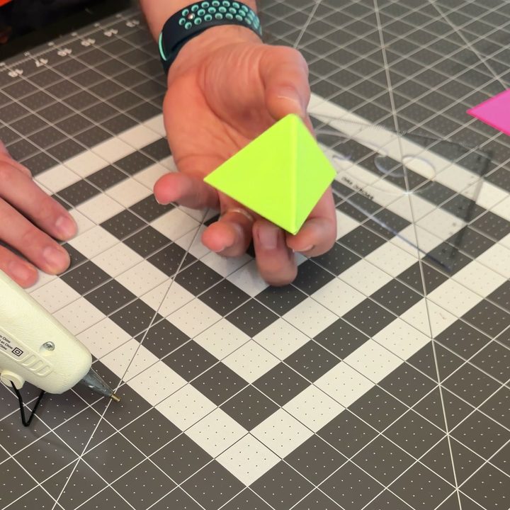 A green paper jewel held in one hand.