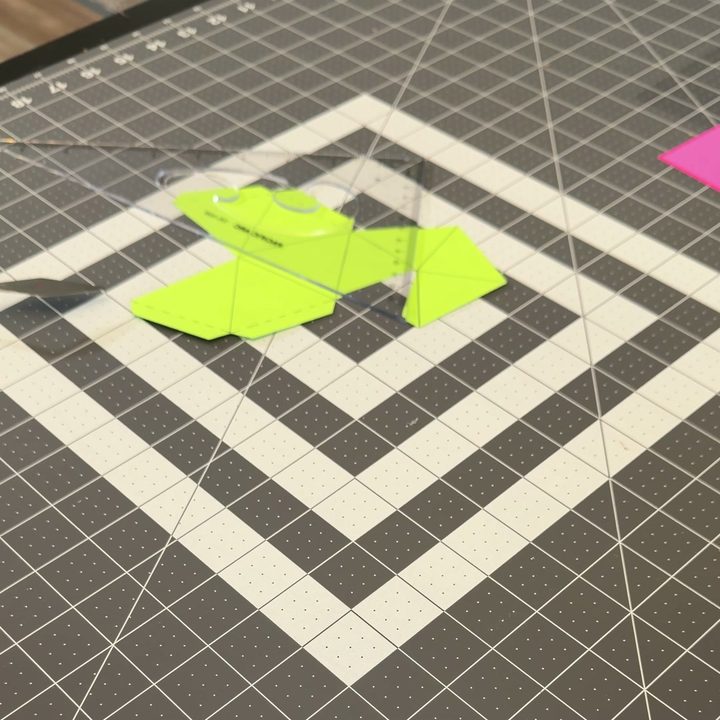 A green paper jewel template cut out on a cutting mat.